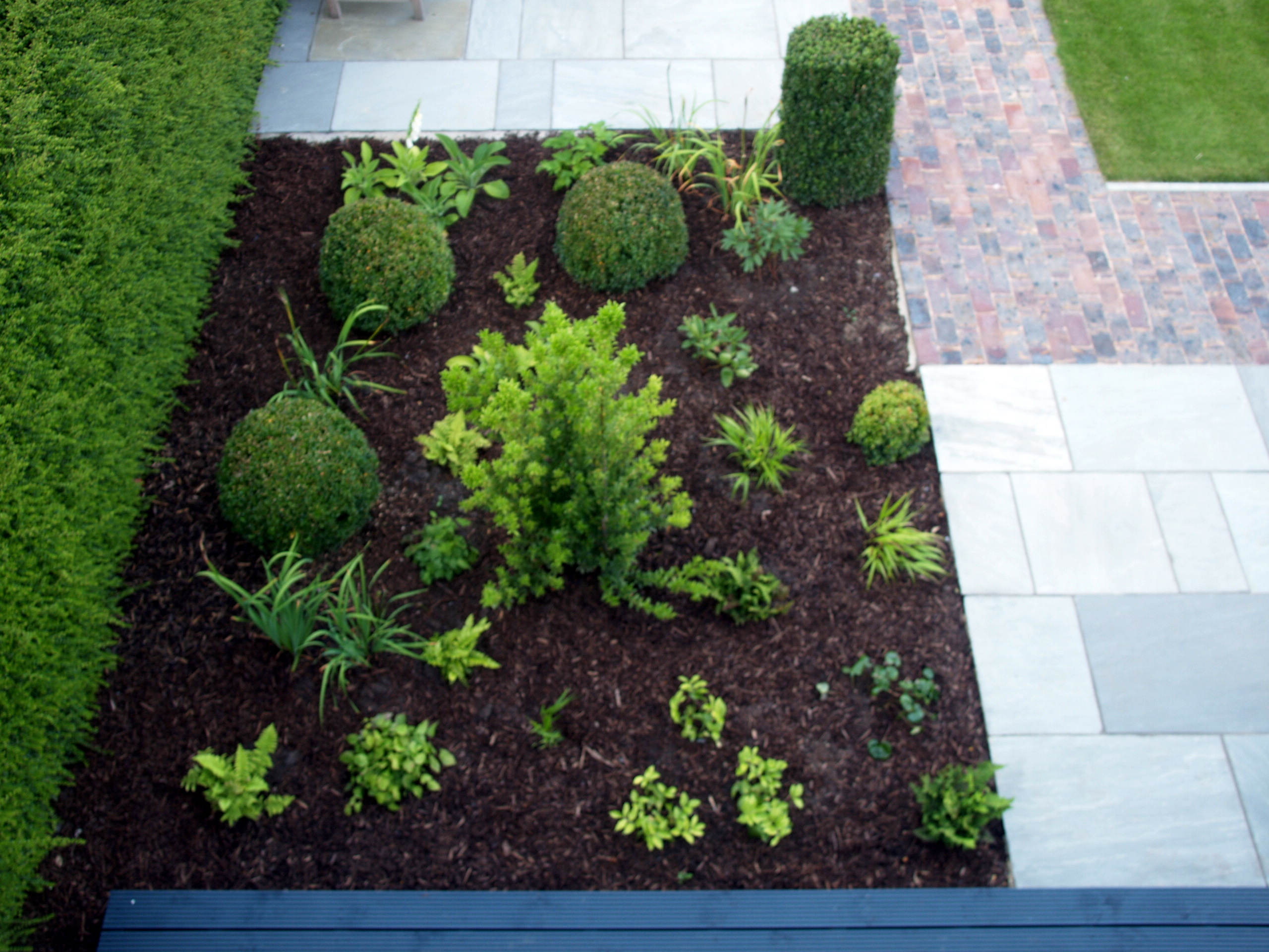 A limited variety of surfaces - grey sandstone, brick pavier, grass and decking (not shown) - create interest without feeling fussy