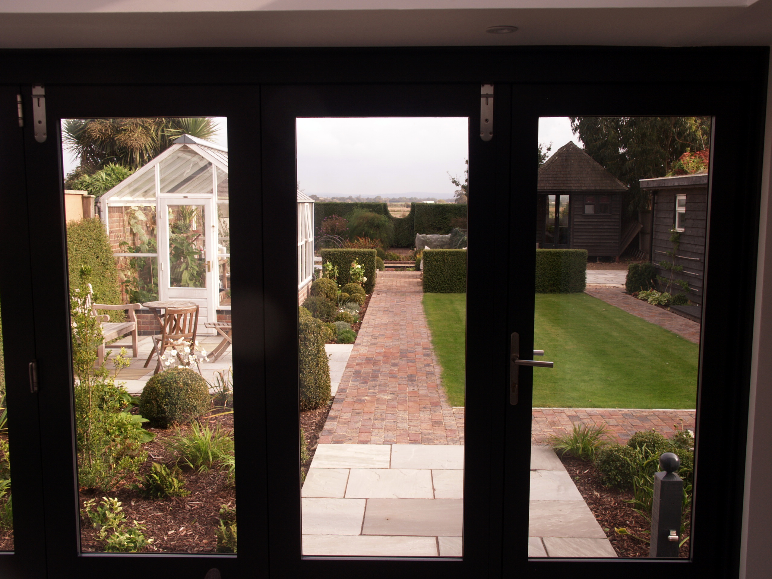 Long view down the garden to borrowed-view in the hedge